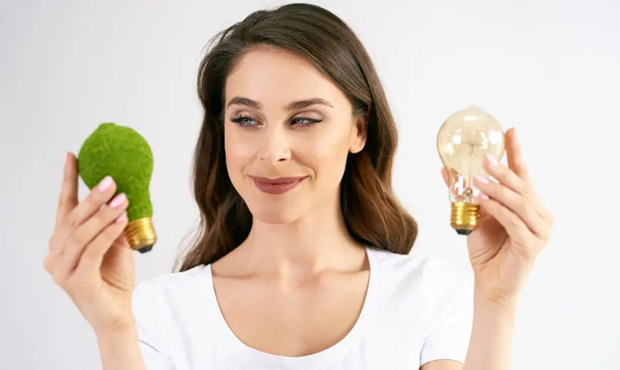 5 ventajas de la integración eléctrica y climatización en tu hogar 3 una mujer sostiene una bombilla con aspecto vegetal en una mano y una bombilla común en la otra simbolizando sostenibilidad energética